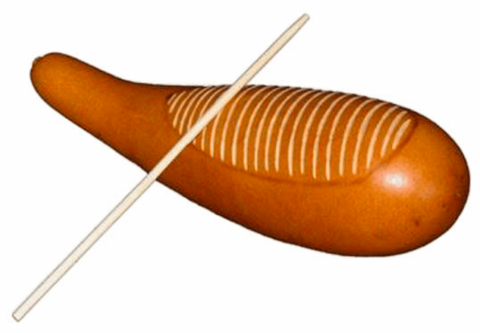 A scraper made from a gourd with ridges carved into it with a stick resting atop of it